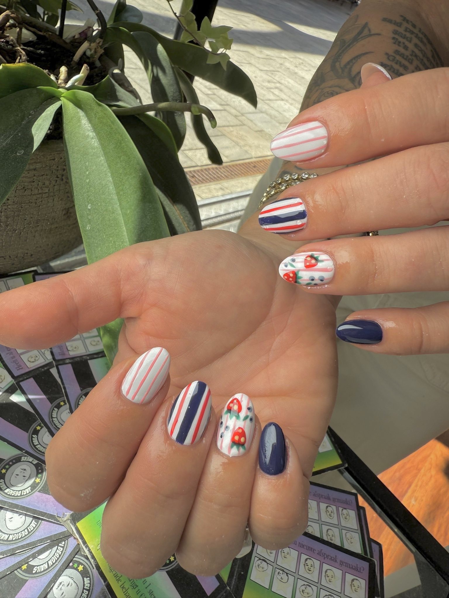 Nail art met strepen in navy, rood en wit en kleine kersjes
