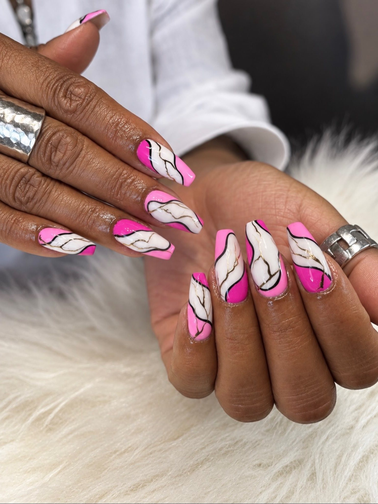 Roze en witte marmernagels met gouden lijntjes op een witte vacht