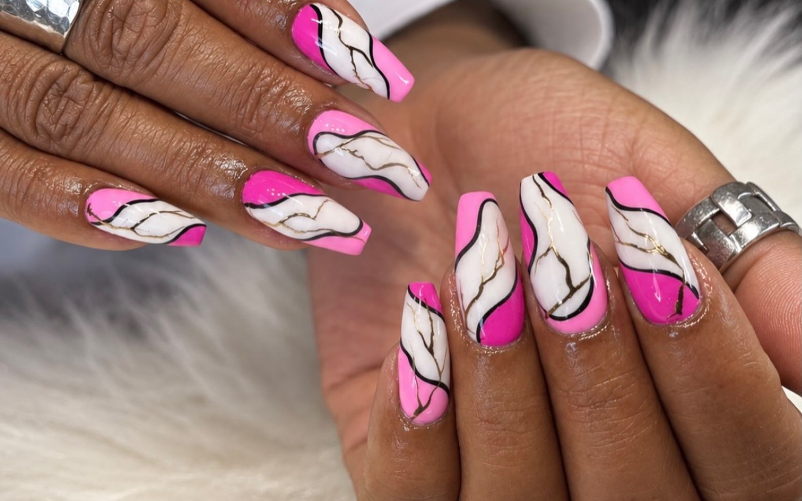 Roze en witte marmernagels met gouden lijntjes op een witte vacht